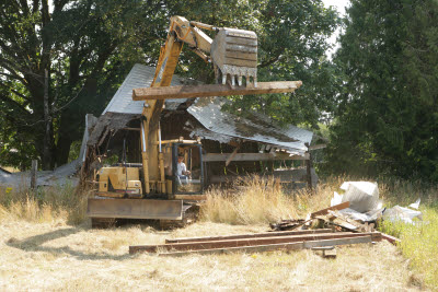 Excavator cleaning up fallen old barn