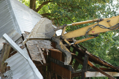 Excavator cleaning up fallen old barn